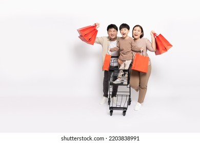 Happy Asian Family Holding Shopping Bag With Shopping Trolley Isolated On White Background, Family And Shopping Mall Concept