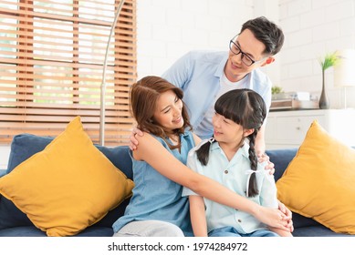 Happy Asian Family Hugging Together On Sofa At Home Living Room.