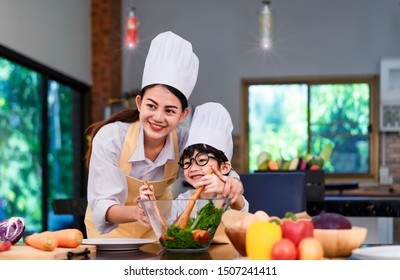 Happy Asian Family In The Kitchen.Mother And Son Help To Make Vegetable Salad.Mom Teaching Kid Boy Cooking Healthy Salad For Dinner.