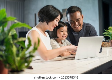 Happy Asian Family Looking At The Computer Together At Home.