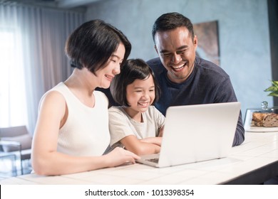 Happy Asian Family Looking At The Computer Together At Home.