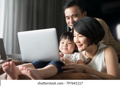 Happy Asian Family Looking At The Laptop Together At Home.