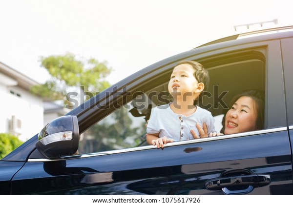 Happy Asian family\
is looking up in the sky and travelling on the road trip, going for\
a drive for vacation