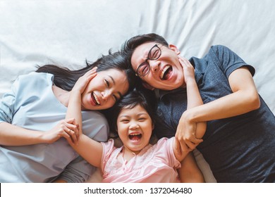 Happy Asian family lying on bed in bedroom with happy and smile, top view