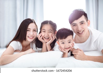 Happy Asian Family Lying On  Bed Together In The Bedroom