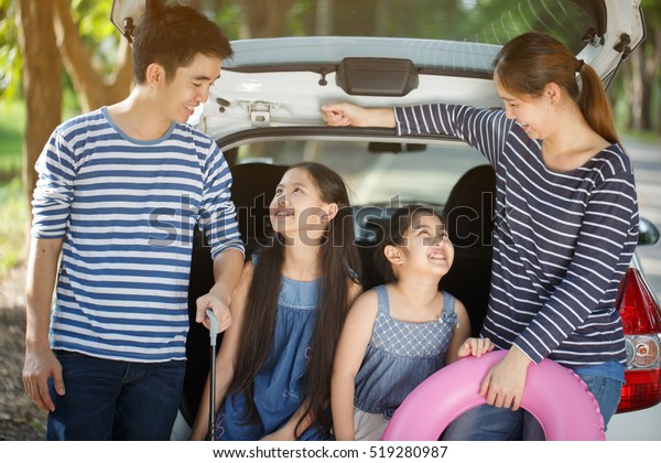Happy Asian family with mini van are smiling and\
preparing for travel on\
vacation