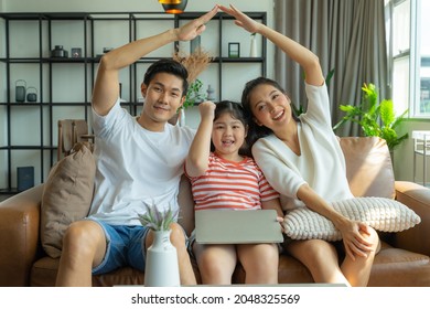 Happy Asian family mom dad with kid daughter using laptop computer together on sofa at home, family home insurance concept