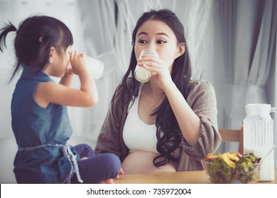 Happy Asian Family Mom And Daughter Drink Milk At Home .