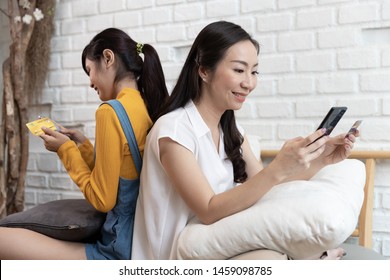 Happy Asian Family Mom And Teenage Daughter Using Smart Phone Online Shopping With Credit Card In A Room With Nature Sunlight At House. Shopping At Home Concept