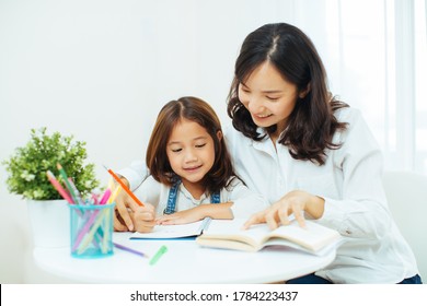 Happy Asian Family. Mother And Daughter Are Learning To Write. Adult Woman Teaches Child