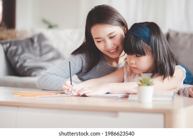 Happy Asian family mother   daughter study drawing together at home in living room
