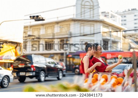 Happy Asian family mother and daughter choosing and buying fresh fruit orange together at Bangkok Chinatown street market for celebrating Chinese Lunar New Year festive. Chinese culture concept.