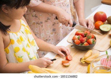 Happy asian family mother and her daughter enjoy prepare freshly squeezed fruits with vegetables for making smoothies for breakfast together in the kitchen.diet and Health concept. - Powered by Shutterstock