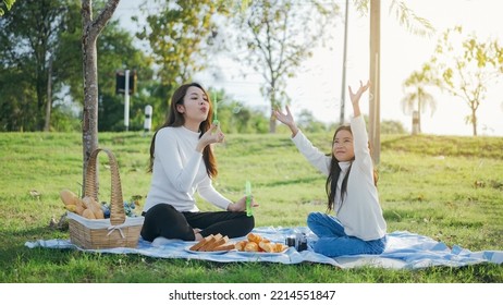 Happy asian family mother and her daughter in the garden, They are having fun playing and blowing bubbles. Family enjoying sunny fall day in nature. - Powered by Shutterstock