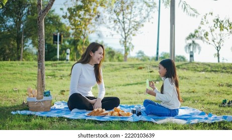 Happy Asian Family Mother And Her Daughter In The Garden, They Are Having Fun Playing And Blowing Bubbles. Family Enjoying Sunny Fall Day In Nature.