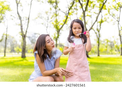 Happy Asian family mother and little daughter playing bubble wand together at public park. Mom and child girl kid enjoy and fun outdoor lifestyle spending time together on summer holiday vacation. - Powered by Shutterstock