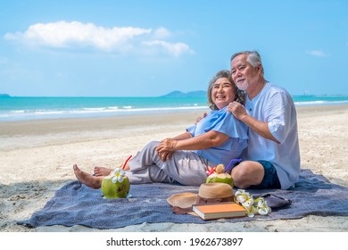 Happy Asian family on beach vacation. Senior couple sitting on blanket have picnic together on sea beach. Healthy elderly husband and wife relax and enjoy outdoor lifestyle activity on summer vacation - Powered by Shutterstock