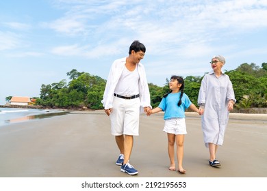 Happy Asian Family On Summer Travel Vacation. Grandfather And Grandmother Walking Together With Grandchild Girl On The Beach. Senior Couple With Granddaughter Enjoy And Having Fun Outdoor Lifestyle