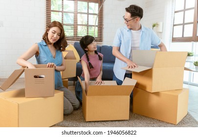 Happy Asian family packing cardboard box during move to new house.