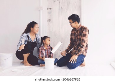 Happy Asian Family Painting Wall At New House.