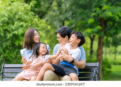 Happy Asian family parent and little kids enjoy and fun outdoor lifestyle on summer holiday vacation. Father, mother and child playing and resting together at park. Family relationship concept. - Powered by Shutterstock