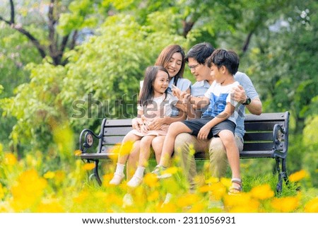 Happy Asian family parent and little kids enjoy and fun outdoor lifestyle on summer holiday vacation. Father, mother and child playing and resting together at park. Family relationship concept.