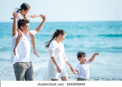 Happy Asian Family Parents With Two Child Boy And Girl Holding Hands And Walking Together On The Beach In Summer Day. Father, Mother And Kids Enjoy And Having Fun In Outdoor Holiday Vacation.