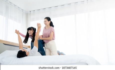 Happy Asian Family People Leisure In Bedroom Together. Father And Mother With Daughter Relaxing On Bed And Enjoy Funny