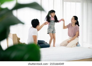 Happy Asian Family People Leisure In Bedroom Together. Father And Mother With Daughter Relaxing On Bed And Enjoy Funny