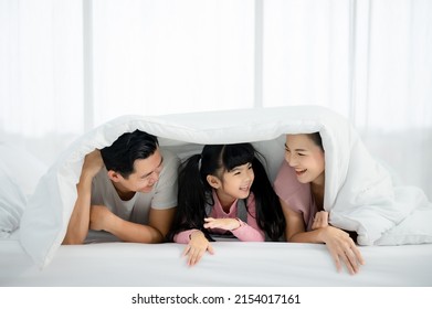 Happy asian family people leisure in bedroom together. Father and mother with daughter relaxing on bed and enjoy funny - Powered by Shutterstock