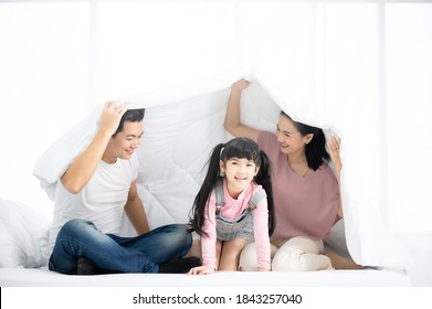 Happy asian family people playing on bed in bedroom at home. Mom and dad with daughter in blanket - Powered by Shutterstock