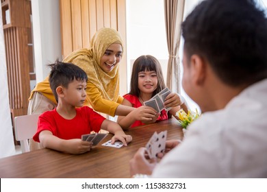 Happy Asian Family Playing Fun Card Game Together At Home