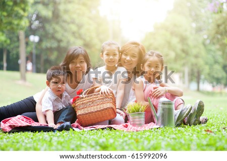 Happy Asian family portrait at nature park, morning outdoor with sun flare.