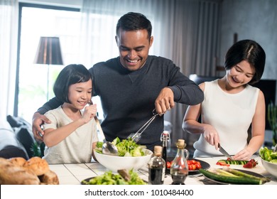 Happy Asian Family Preparing Food In The Kitchen.