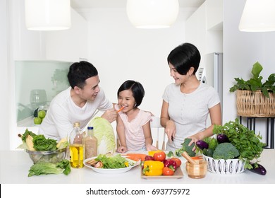 Happy Asian Family Preparing Food In The Kitchen.