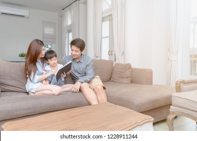 Happy asian family reading storybook at home in the living room, learning and education concept - Powered by Shutterstock