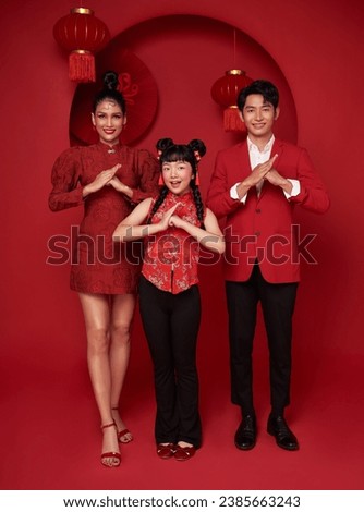 Happy asian family in red casual attire with gesture of congratulation greeting happy new year 2024 on Decoration traditional red background.