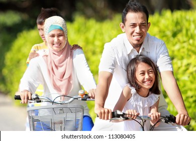 Happy Asian Family Riding Bikes In The Beautiful Morning