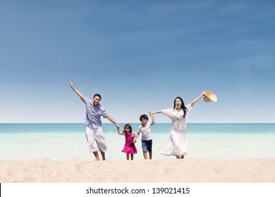 Happy Asian Family Running At Beach