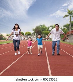 Happy Asian Family Running Together On The Stadium Track