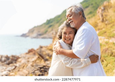 Happy Asian family senior couple with gray hair relaxing and hugging each other on mountain cliff at sunset. Retirement elderly people enjoy outdoor lifestyle travel nature ocean on summer vacation. - Powered by Shutterstock