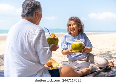 Happy Asian family senior couple travel nature ocean on summer beach holiday vacation. Healthy elderly retired people enjoy outdoor lifestyle drinking coconut water at tropical beach in sunny day. - Powered by Shutterstock