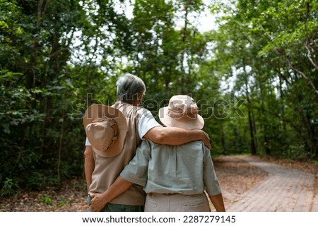 Happy Asian family senior couple hiking together in tropical forest in sunny day. Retired elderly people man and woman enjoy and fun outdoor activity lifestyle travel nature on summer holiday vacation