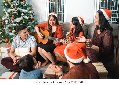 Happy Asian Family Singing And Playing Guitar Together On Christmas Eve