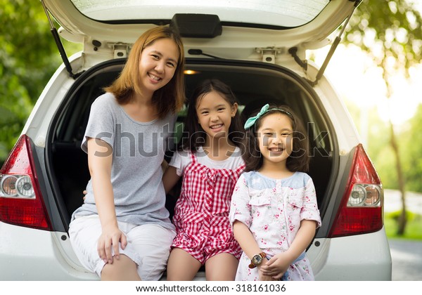 Happy Asian family\
sitting in the car