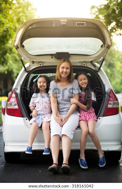 Happy Asian family\
sitting in the car