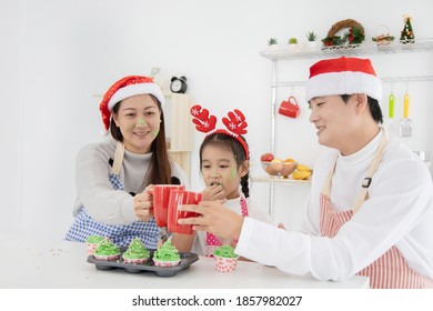 Happy Asian Family Sitting At Kitchen Drinking Coffee And Eating Cup Cake On Christmas Day