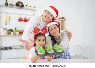 Happy Asian Family Sitting At Kitchen Holding Cup Cake Together In Christmas Day