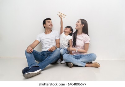 Happy Asian Family Sitting On The Floor And Playing Toy Airplane  Together. Family And Childhood Concept.