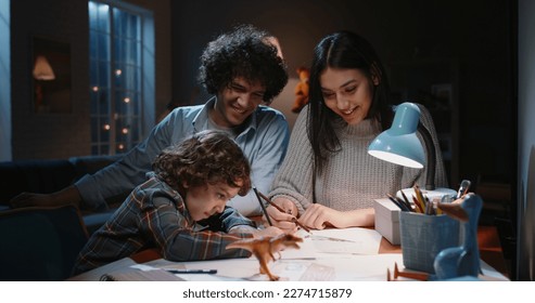 Happy asian family spending time at home together  Young parents teaching their little kid and curly hair how to draw  having fun    happy family  togetherness concept 